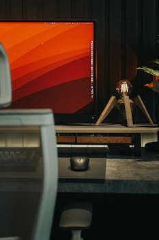 A minimalist workspace featuring a computer, mouse, and sleek lamp on a modern desk.