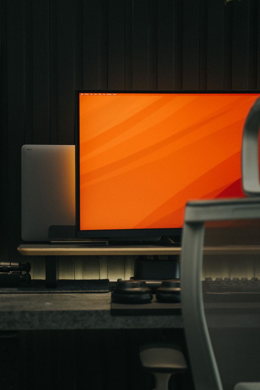 A stylish indoor workspace featuring a monitor with an orange screen, ideal for tech setups.