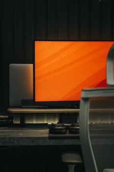 A stylish indoor workspace featuring a monitor with an orange screen, ideal for tech setups.