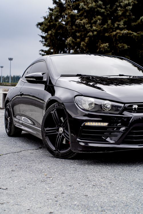 Free A sleek black Volkswagen Scirocco parked outdoors showcasing modern design and elegance. Stock Photo