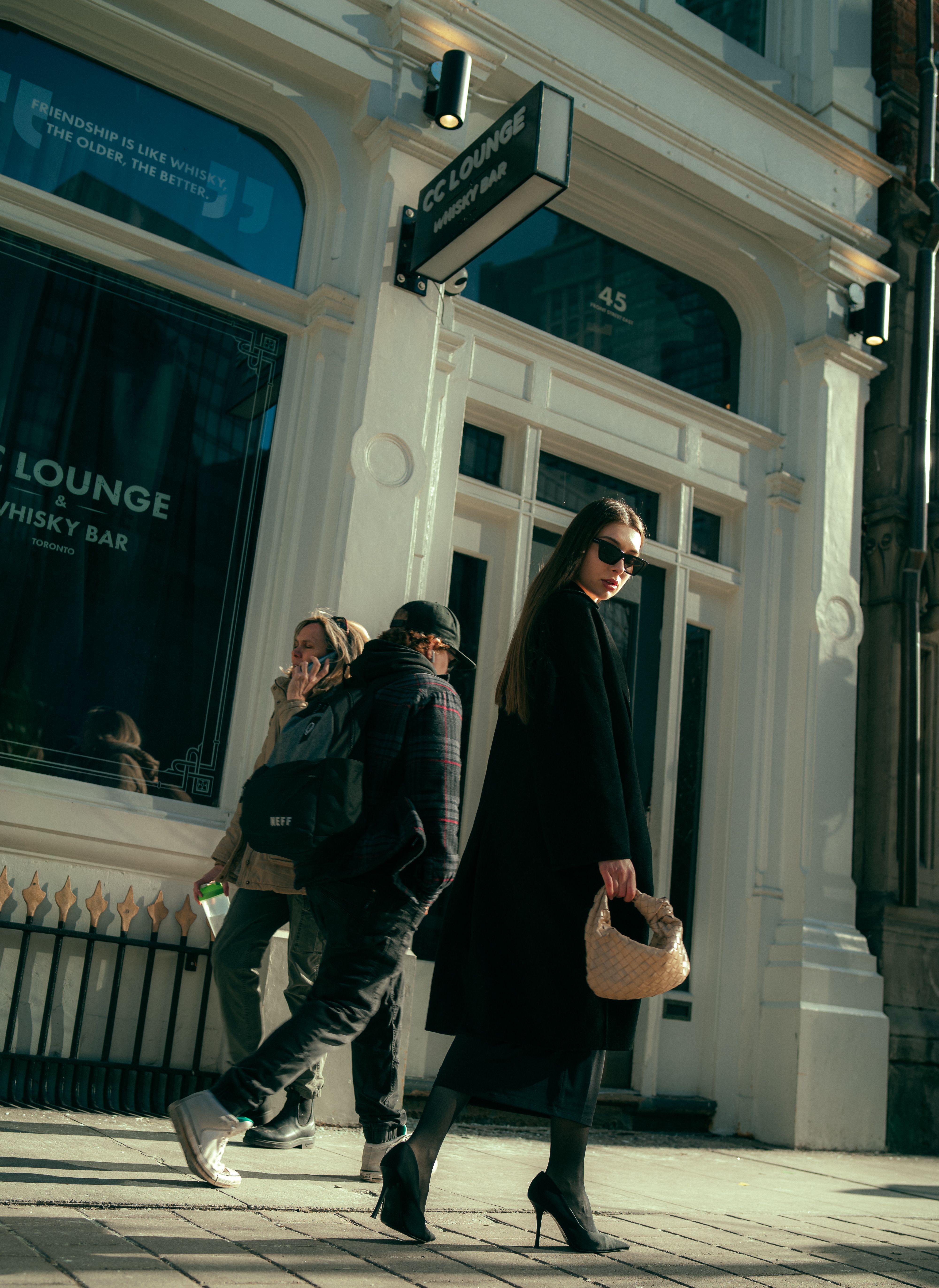 Woman in Black Coat and High Heels Walking on Sidewalk · Free Stock Photo