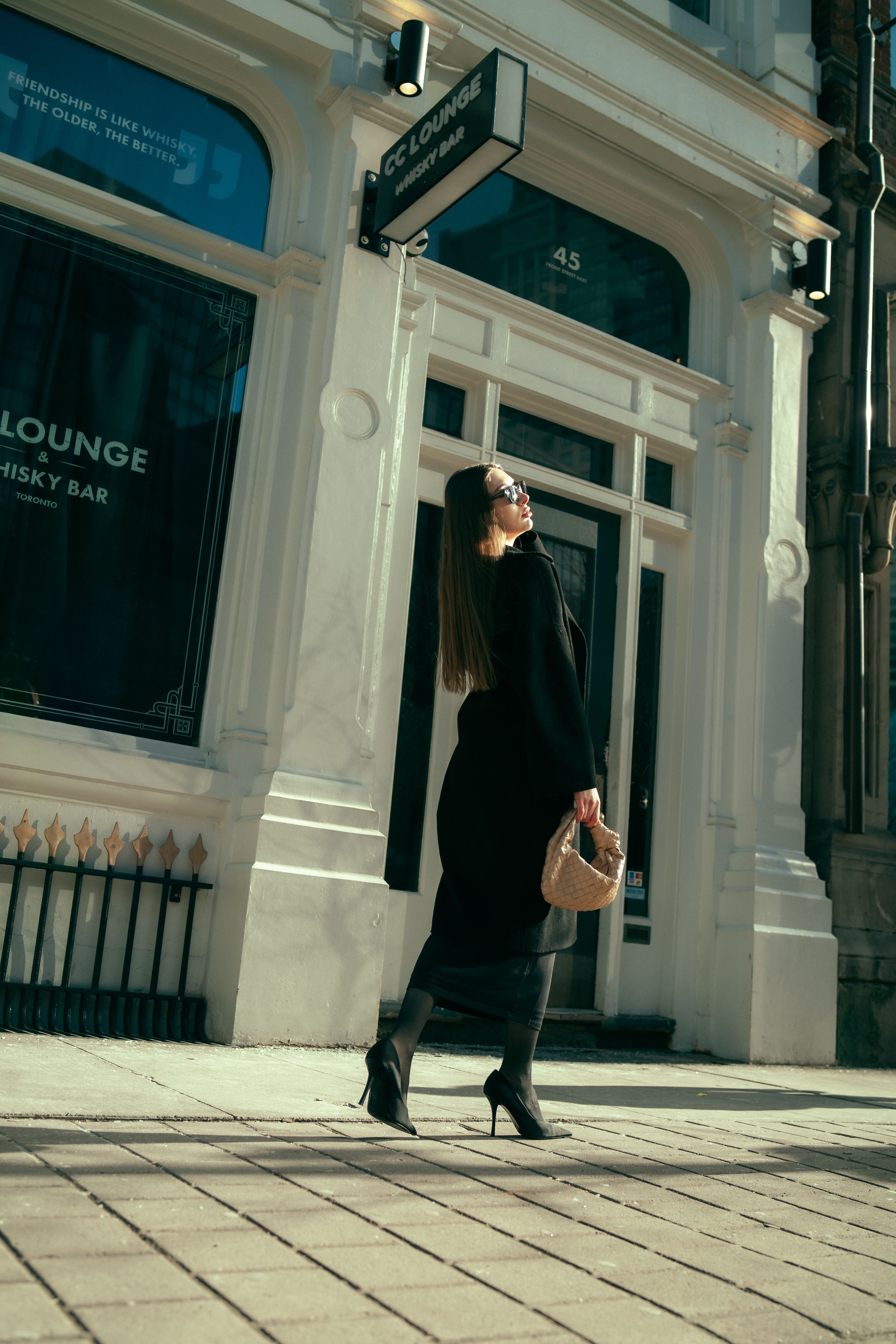 Woman in Black Coat and with Bag Standing on Sidewalk · Free Stock Photo