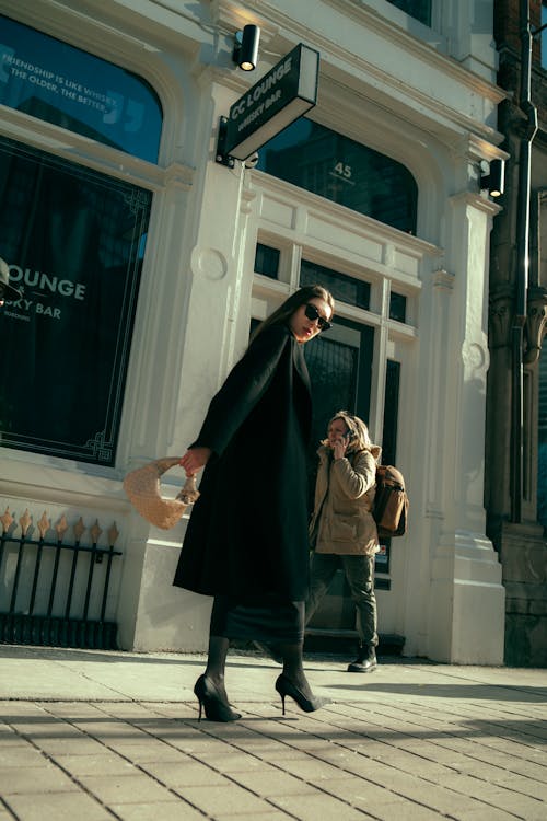 A woman in a black coat walking down a sidewalk
