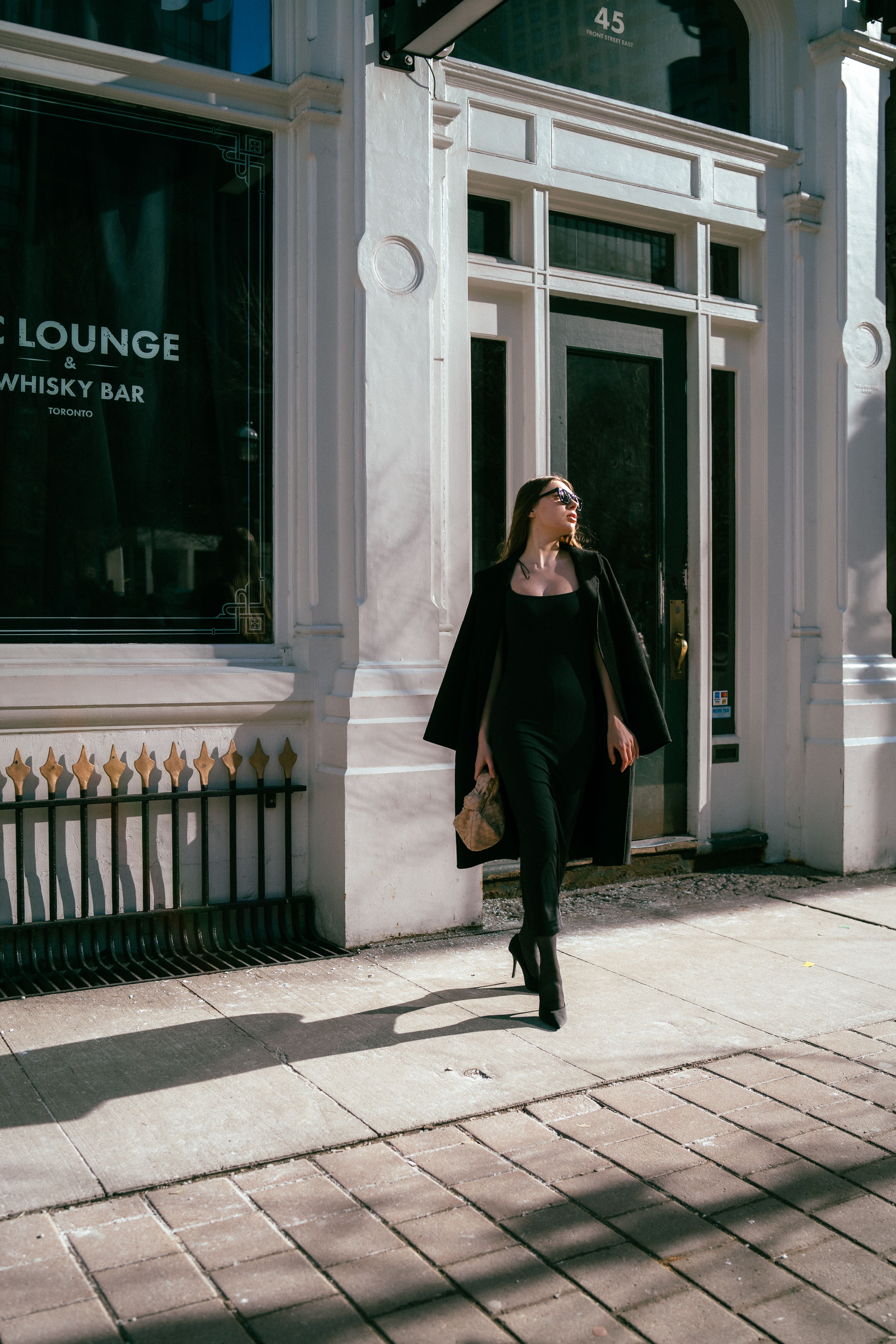 Woman in Black Coat Walking on Sidewalk · Free Stock Photo