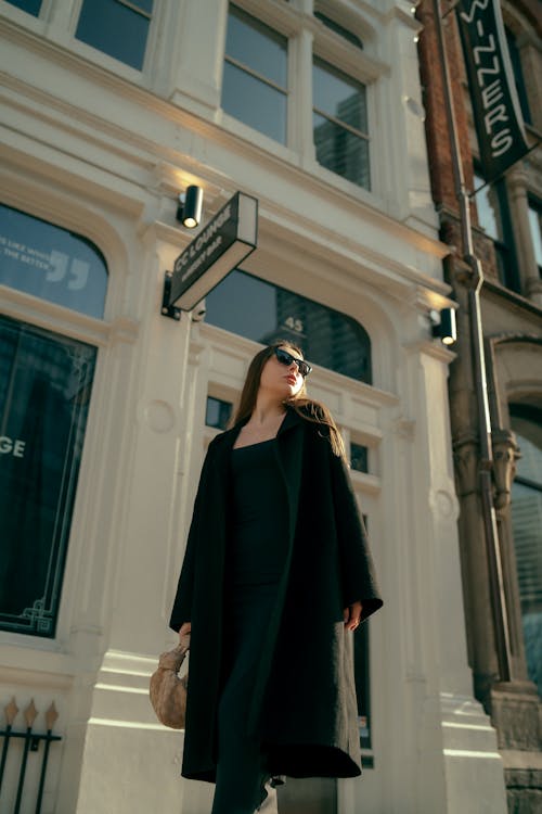 A woman in a black coat and sunglasses walking down the street