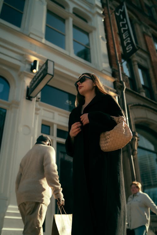 A woman in a black coat and sunglasses walking down a street