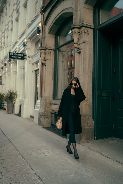 A woman in a black coat walking down a city street