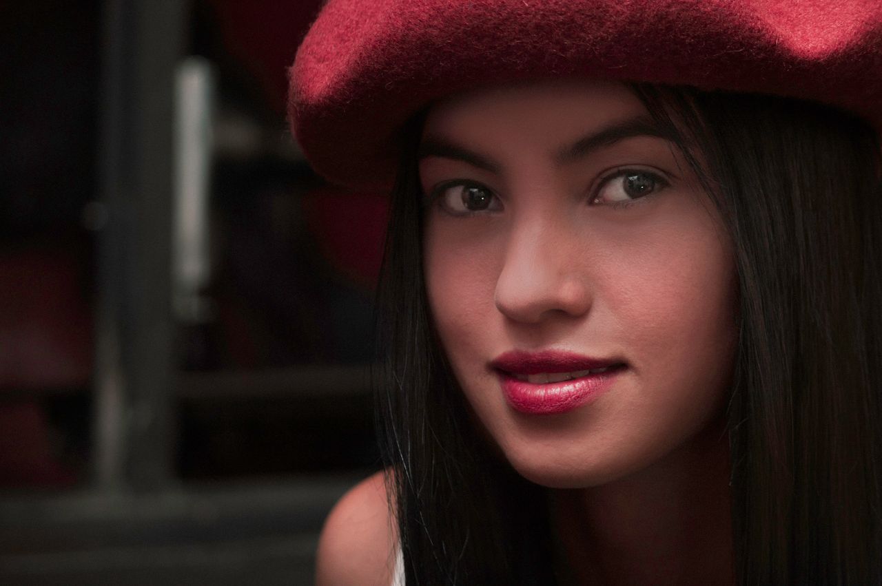 a close up portrait of a woman in a red beret with long hair and strik