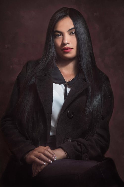 A woman with long black hair and a black coat