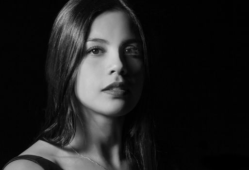 Black and white studio portrait of a woman with long hair and a serene expression.