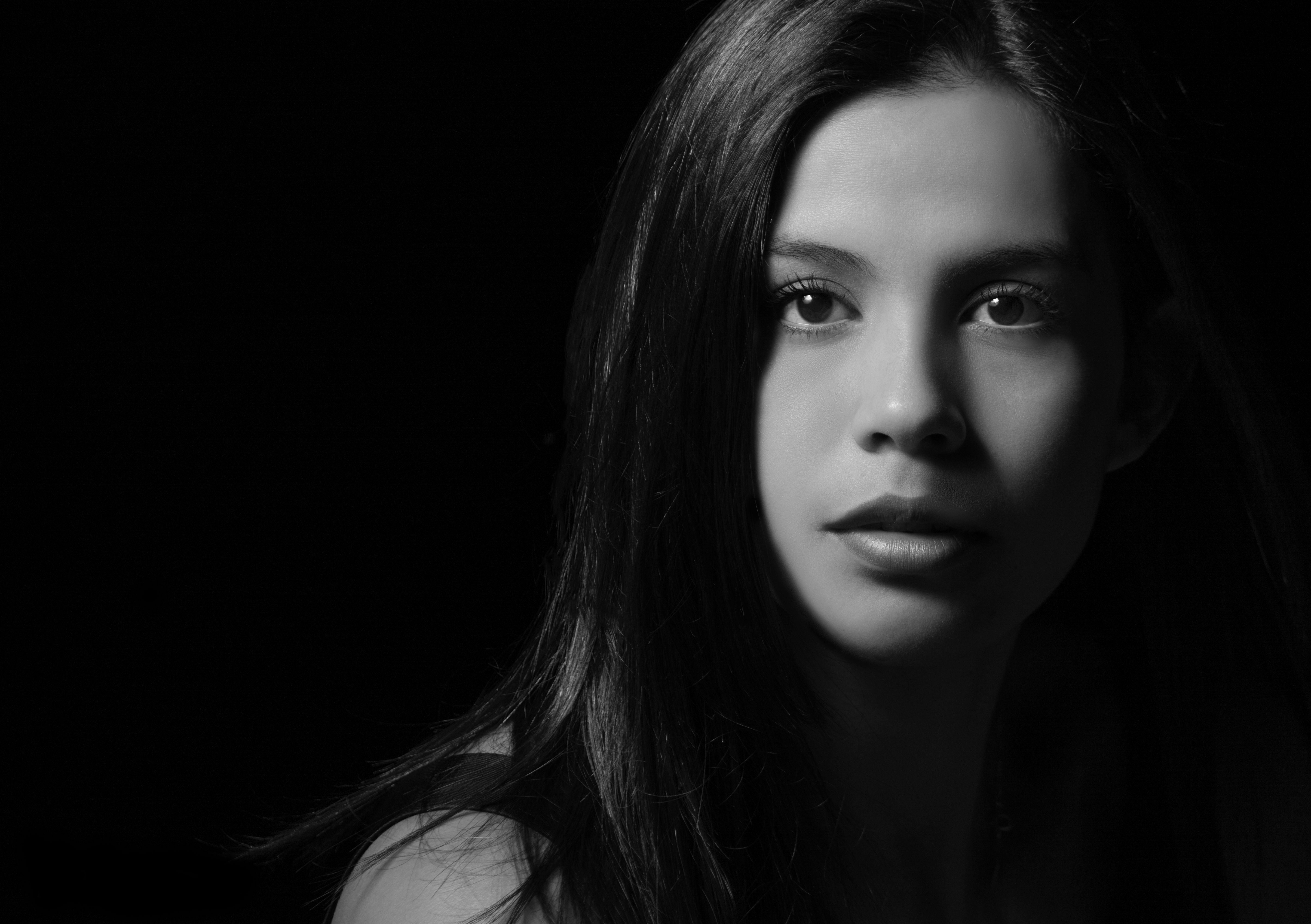 Artistic black and white studio portrait of a woman with long hair.
