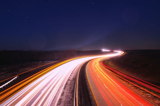 Captivating long exposure of car lights on a highway near Matfield Green, KS under a clear night sky.