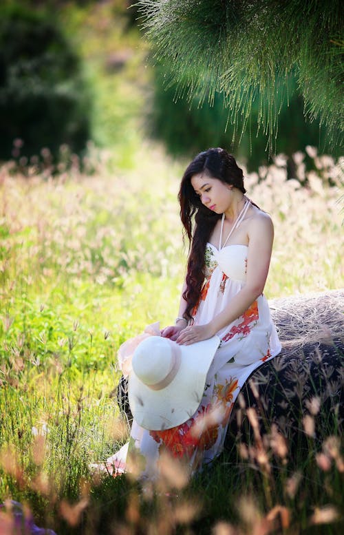 Sitting Woman Puts Her White Sun Hat on Her Lap While Holding It