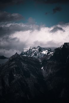 A striking view of snow-capped mountains beneath a cloudy sky, creating a dramatic landscape.