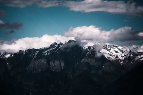 Free Dramatic view of snow-capped mountain peaks beneath a striking cloudy sky, showcasing nature's grandeur. Stock Photo