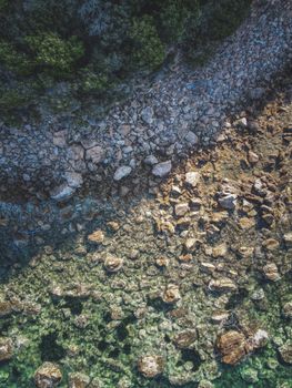 Stunning aerial shot of a rocky shoreline with crystal clear water and lush greenery.