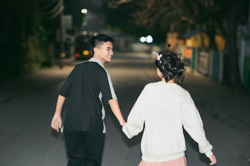 Two people holding hands walking down a street