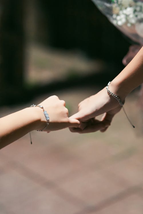 Two people holding hands with bracelets on their wrists