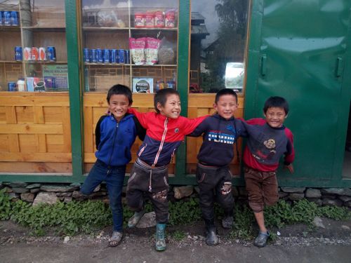 Free Four smiling children pose happily outside a local shop in Delhi, India. Stock Photo