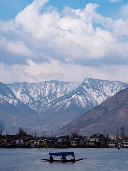 Beautiful snowy mountain backdrop with a calm lake and a boat, ideal for nature lovers.