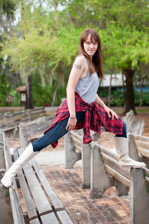 Woman in White Cowboy Boots Standing on the Backs of Benches