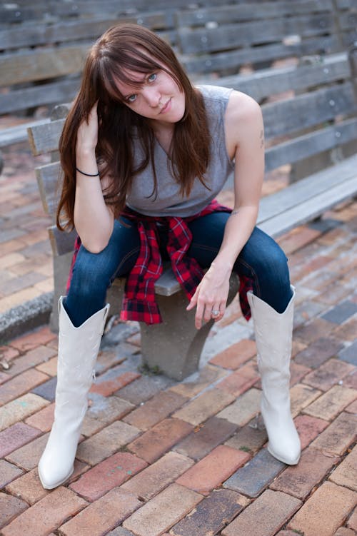 Young Woman in White Cowboy Boots Sitting on a Bench
