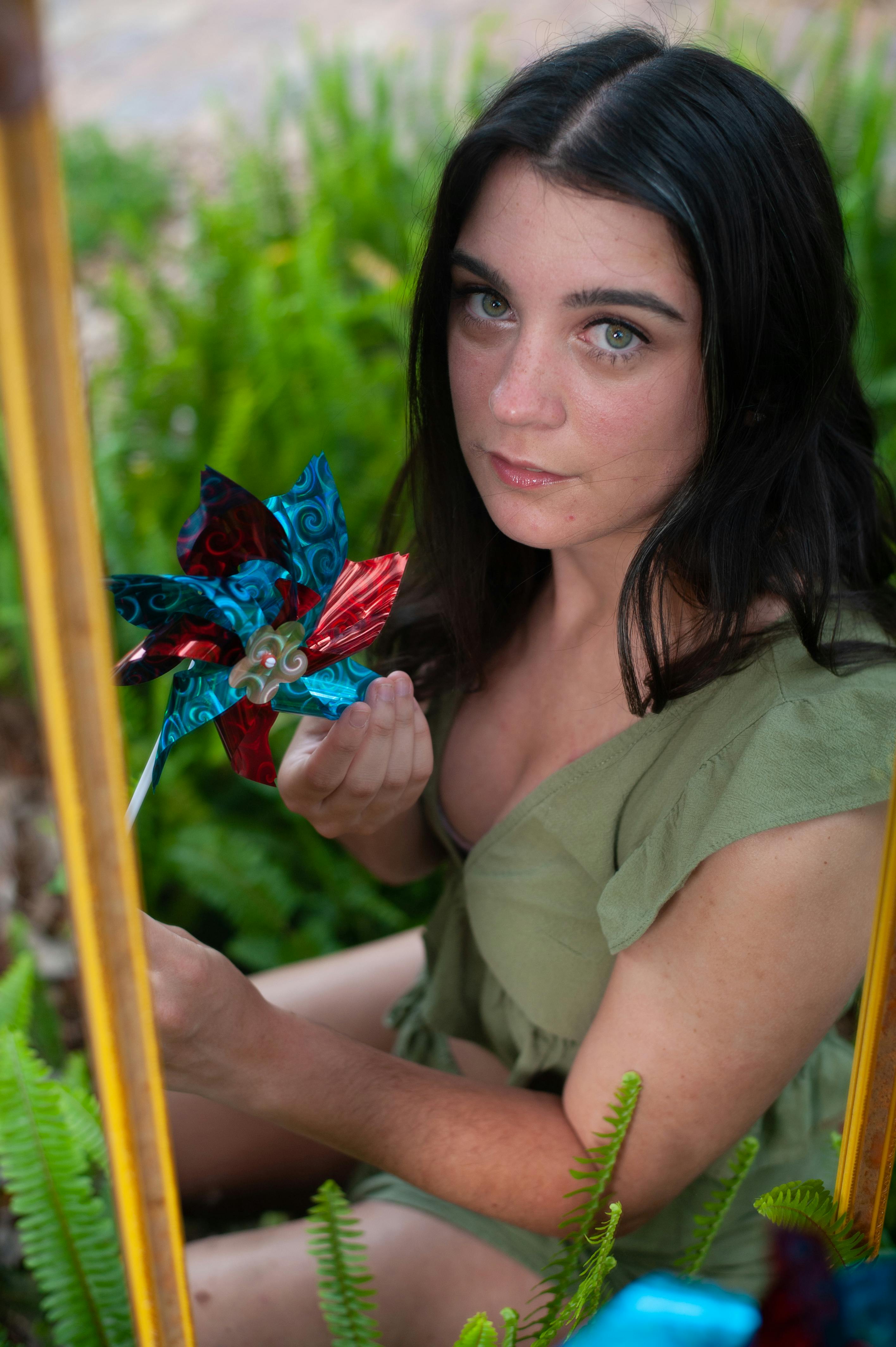 woman sitting and holding colorful toy fan