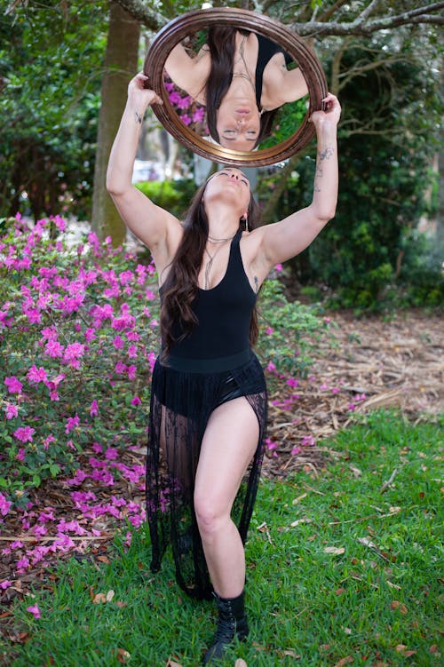 Model in Tank Top and Black Chiffon Skirt Holding a Mirror Above Her Head