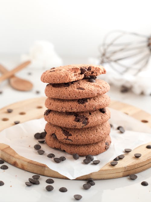 A stack of chocolate chip cookies on a wooden cutting board