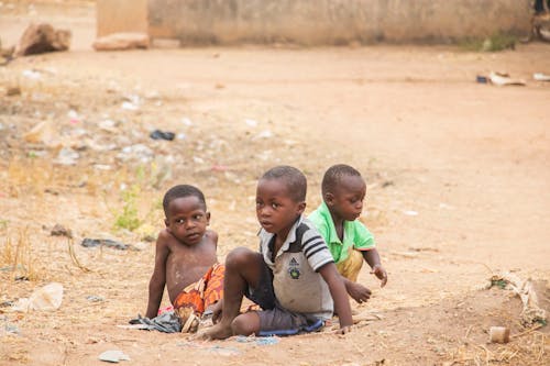 Three Children Sitting on Dirt