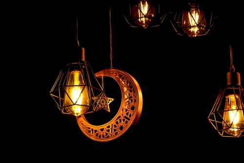 Free A mystical display of decorative lanterns with crescent and star motifs glowing in darkness. Stock Photo