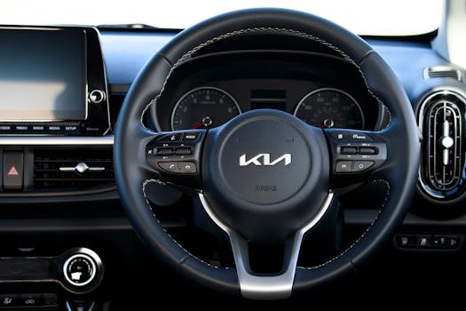 Close-up of a Kia steering wheel and dashboard showcasing modern car interior design.