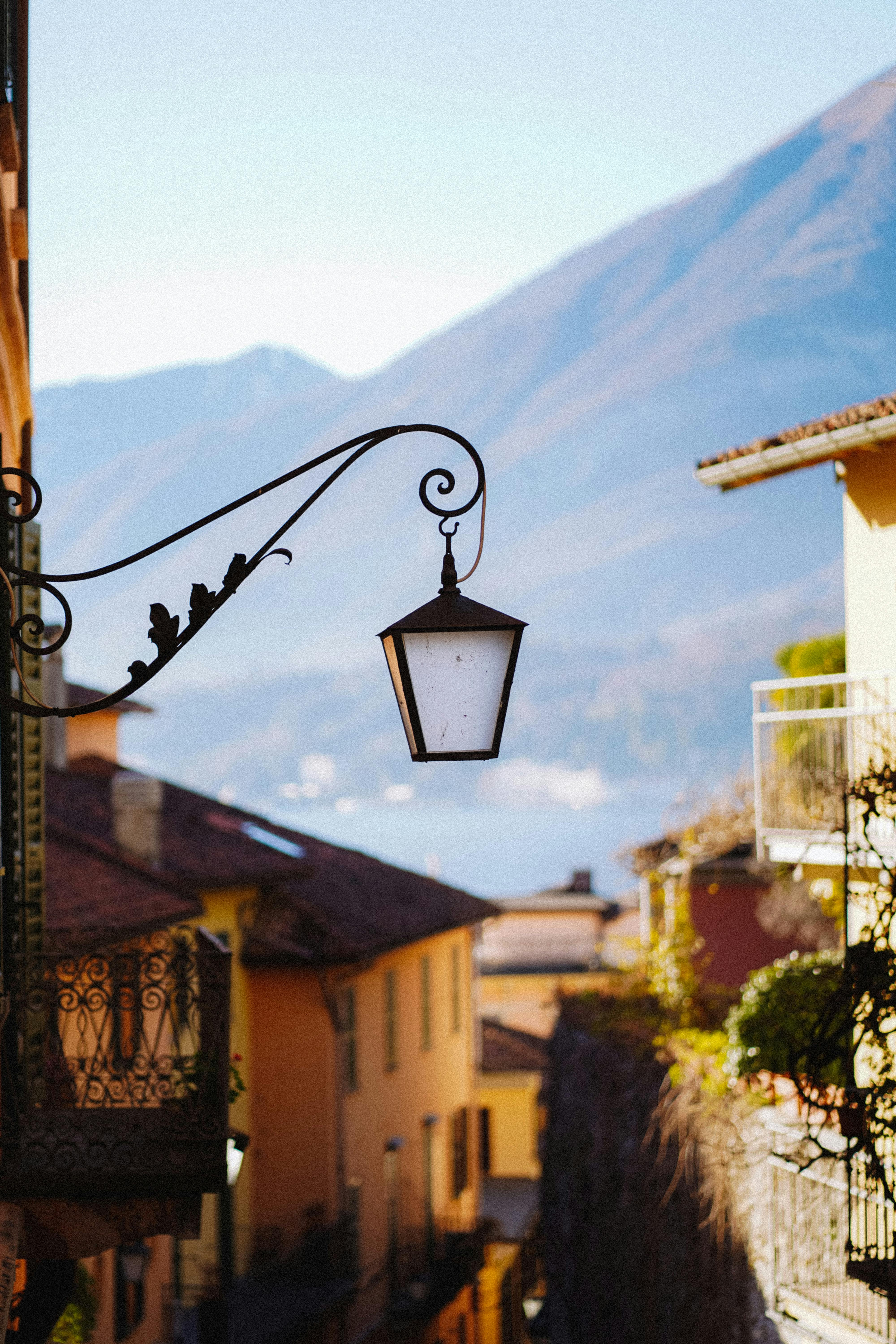 A vintage streetlight in a picturesque old town with mountain backdrop.