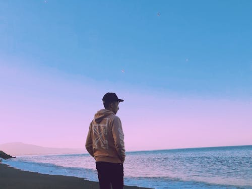 Man In Hoodie Standing On Seashore