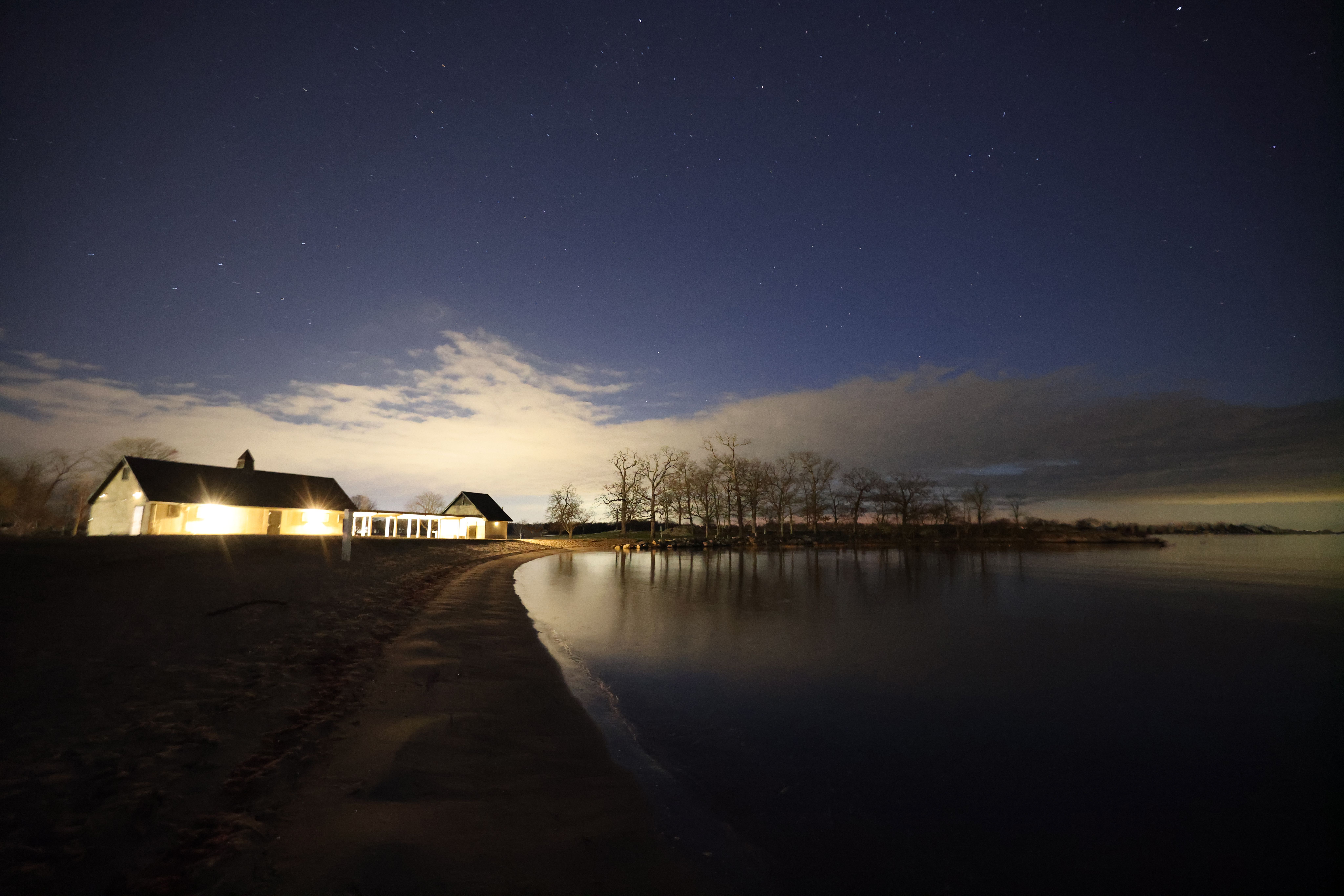 Tältläger vid sjöstrand under stjärnhimmel