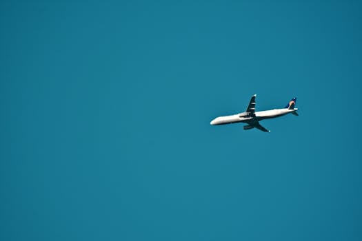 A commercial airplane flying against a clear blue sky, capturing the essence of travel and aviation.
