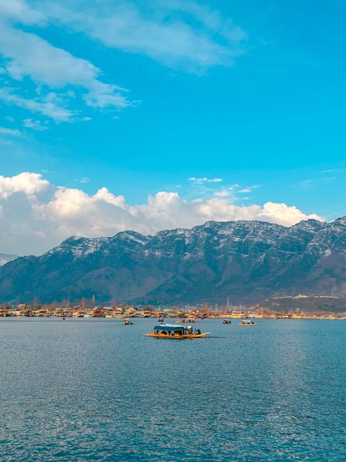 Free Tranquil view of Dal Lake with boats and mountains under a blue sky in Srinagar. Stock Photo