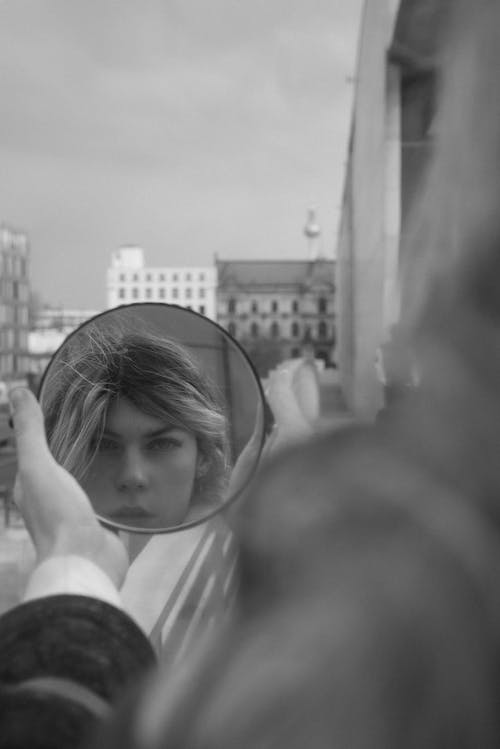 A woman is looking at her reflection in a mirror