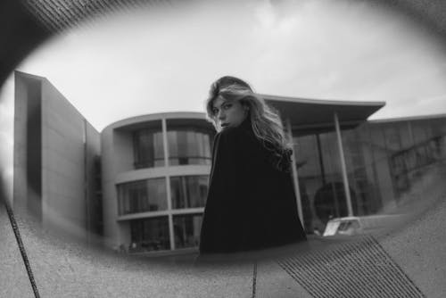 A woman in a black coat is standing in front of a building