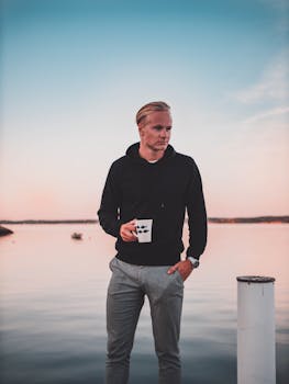 黄昏时分，一位时尚的年轻人在湖边喝着咖啡