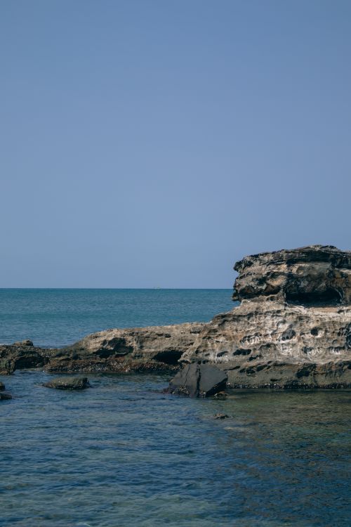 Free Serene coastal view featuring rocky cliffs and a calm sea under a clear blue sky. Stock Photo