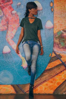 一位时尚女子身穿休闲装，靠在色彩缤纷的涂鸦墙前摆姿势