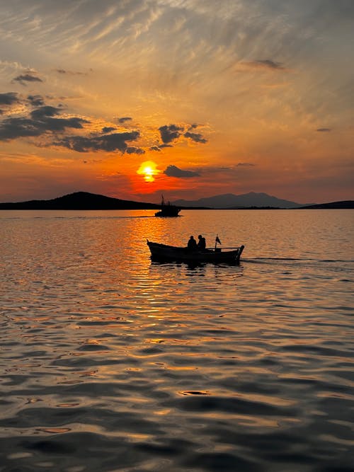 Two people in a boat at sunset on a lake