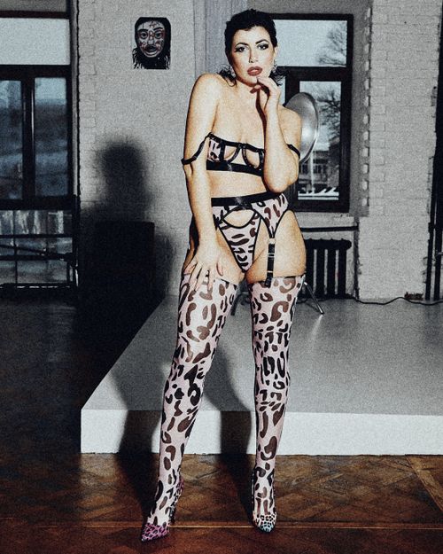 Free Fashionable woman posing in leopard print lingerie and boots indoors, showcasing bold style. Stock Photo