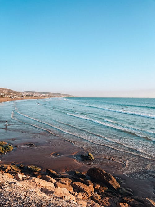 A beach with waves and rocks in the background