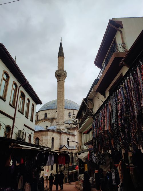 Free View of a mosque in Bolu, Türkiye framed by market stalls under a cloudy sky. Stock Photo