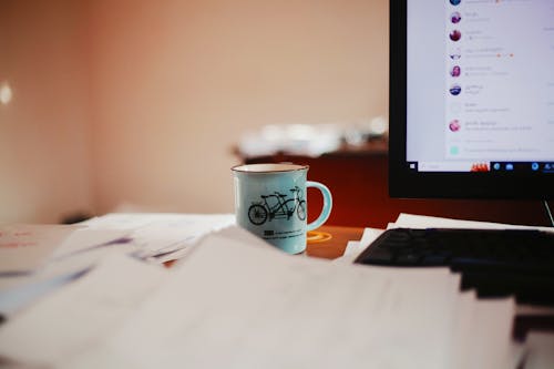 A mug on a desk next to a computer monitor
