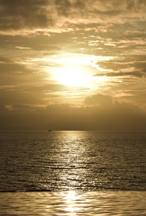 Free A serene sunset over the ocean, casting golden reflections on the water surface. Stock Photo