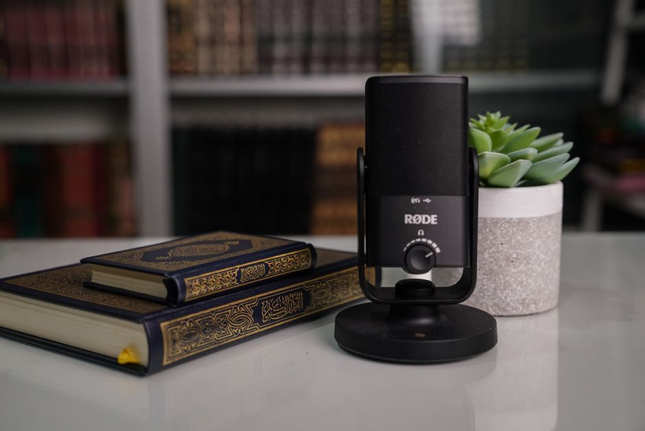 Close-up of books with a Røde microphone and succulent on a desk.
