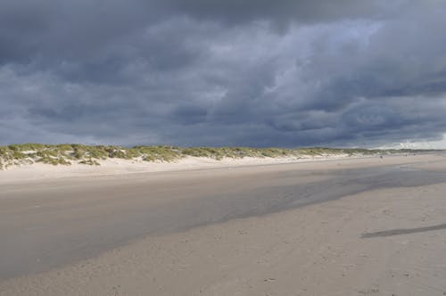 Foto profissional grátis de areia, beira-mar, céu nublado